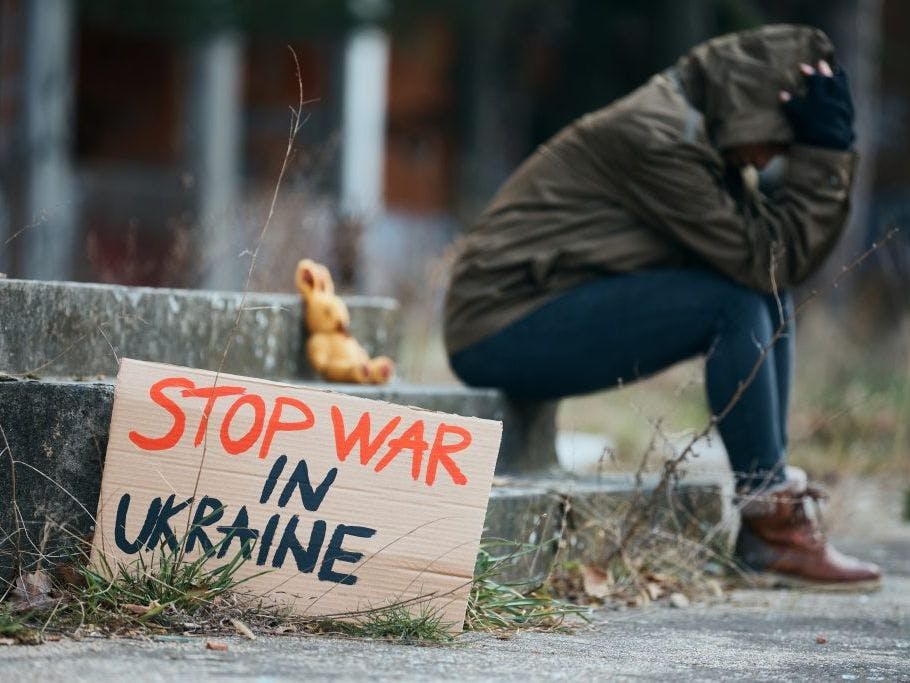 Bilde av Stopp krigen i Ukraina-plakat og en person i bakgrunnen